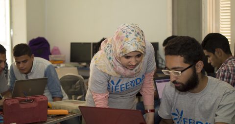 Two people with IEEE shirts on looking at a laptop