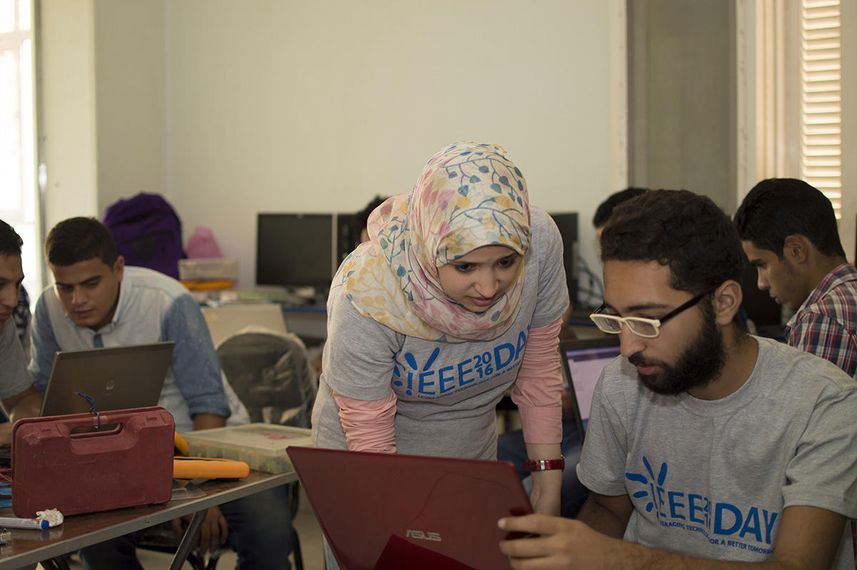 Two people with IEEE shirts on looking at a laptop
